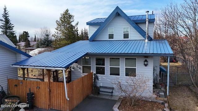 view of front of house featuring metal roof, a standing seam roof, and fence