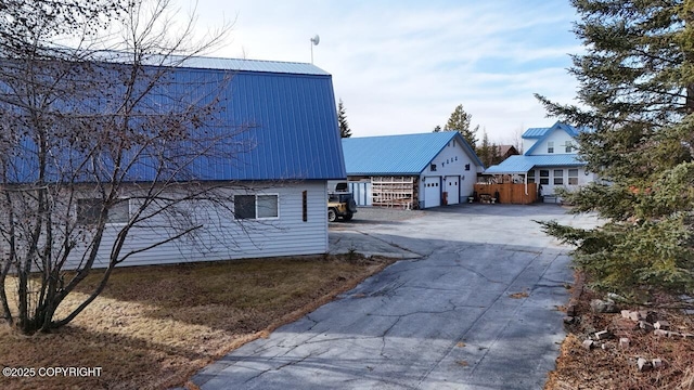 view of side of home with a gambrel roof, metal roof, and a detached garage