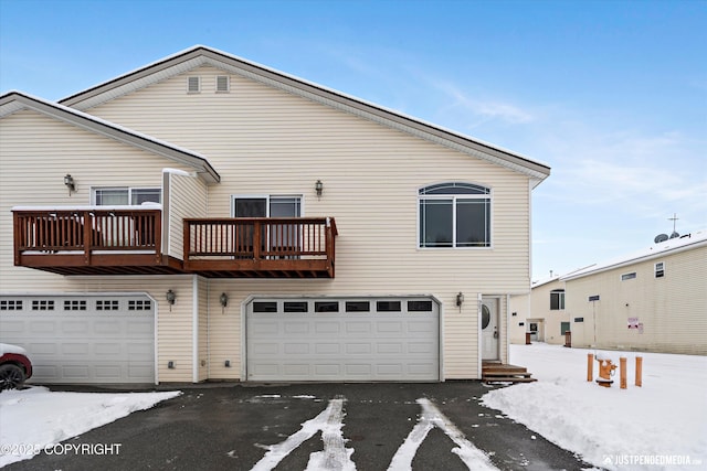 snow covered rear of property with an attached garage