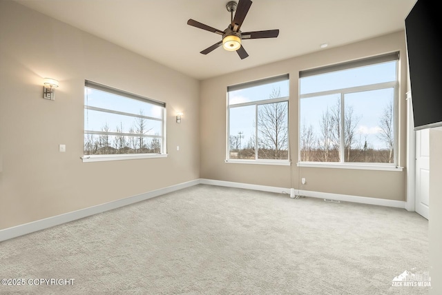 carpeted spare room featuring baseboards and a ceiling fan