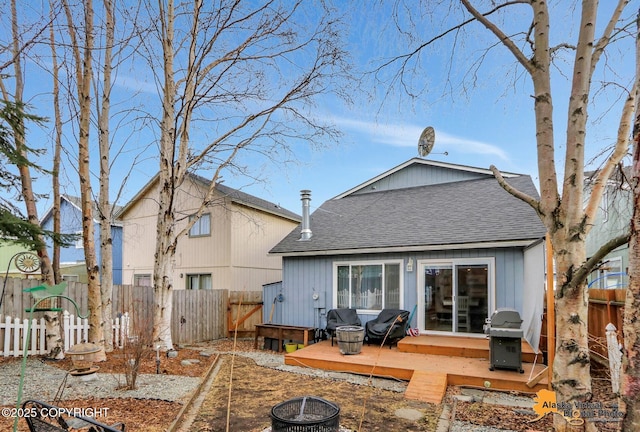 back of house featuring a shingled roof, a fenced backyard, a fire pit, and a deck