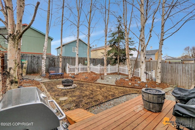 view of yard featuring a deck, a fenced backyard, and a fire pit