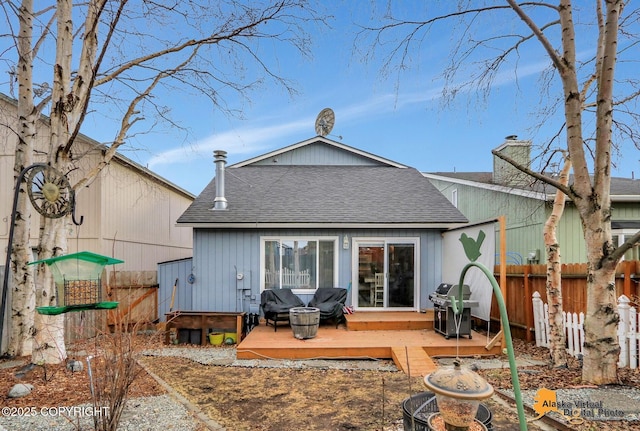 rear view of property featuring a deck, roof with shingles, a chimney, and fence