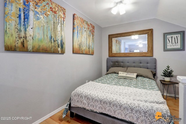 bedroom with vaulted ceiling, baseboards, and wood finished floors