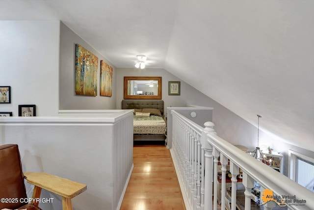 hall featuring vaulted ceiling, light wood finished floors, and an upstairs landing