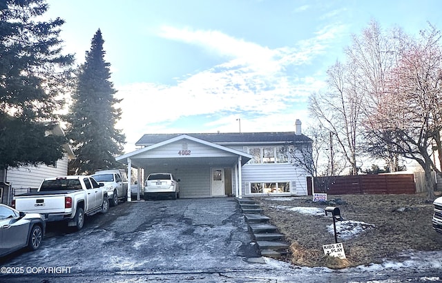 view of front of property with driveway, an attached carport, and fence