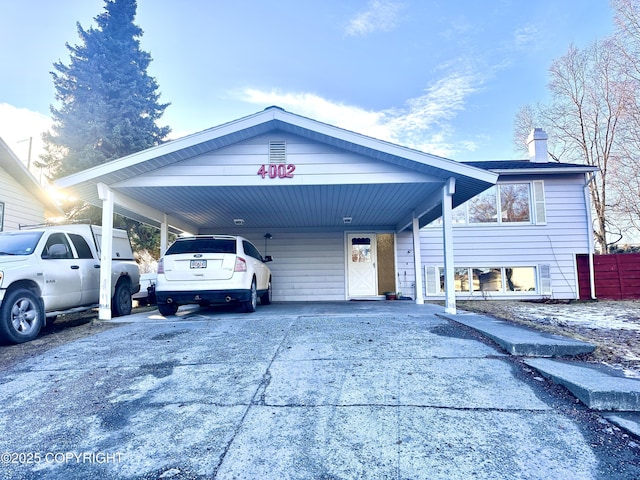 view of front of house with a chimney, an attached carport, and concrete driveway