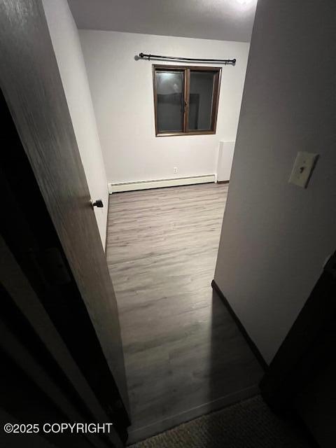 hall with baseboard heating and wood finished floors