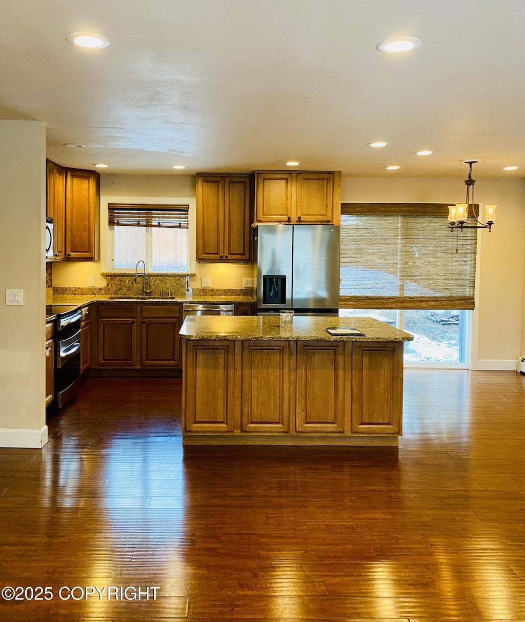 kitchen with stainless steel appliances, a sink, dark wood-type flooring, a kitchen island, and recessed lighting