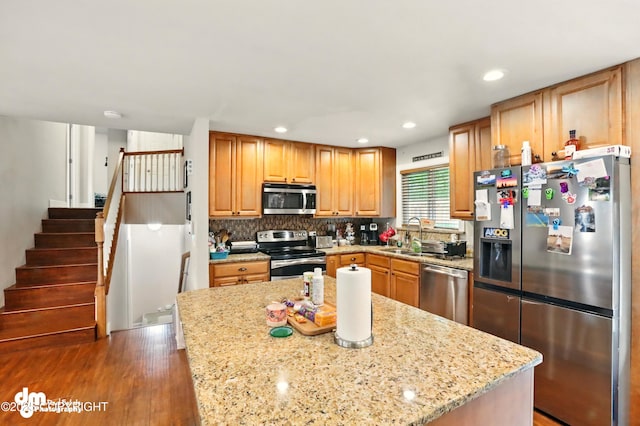 7210 Akutan Cir, Anchorage, AK 99504 - kitchen with stainless steel appliances, light stone countertops, wood finished floors, backsplash, and recessed lighting