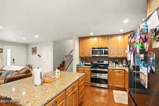 7210 Akutan Cir, Anchorage, AK 99504 - kitchen featuring stainless steel appliances, wood finished floors, recessed lighting, light stone counters, and tasteful backsplash