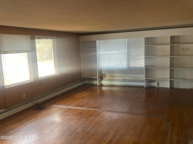 unfurnished room featuring a textured ceiling, baseboard heating, and hardwood / wood-style flooring