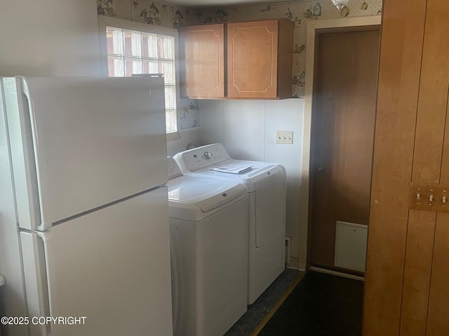 laundry room featuring washing machine and clothes dryer, cabinet space, and wallpapered walls