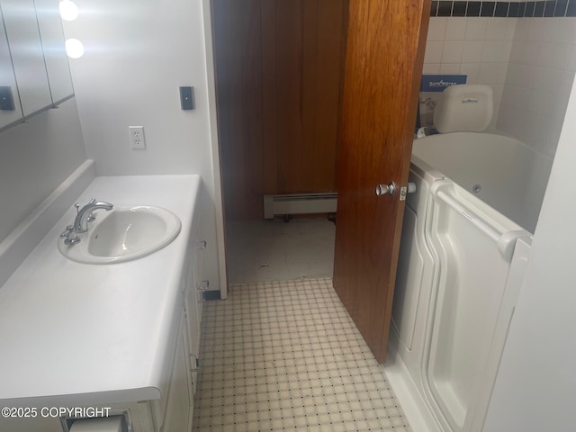 bathroom with a tub to relax in, a baseboard radiator, vanity, tile patterned floors, and washer / clothes dryer