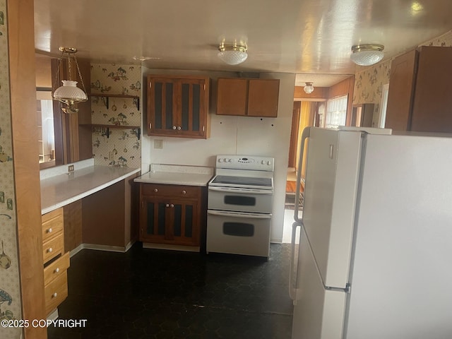 kitchen with white appliances, light countertops, brown cabinetry, glass insert cabinets, and wallpapered walls