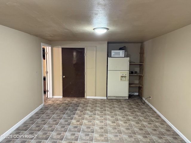 unfurnished bedroom featuring freestanding refrigerator and baseboards