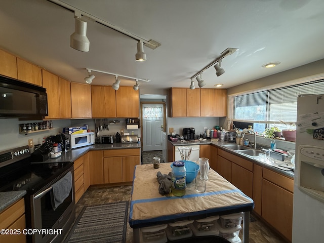 kitchen featuring white appliances, dark countertops, a sink, and a healthy amount of sunlight