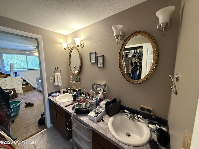 full bath with double vanity, a textured ceiling, and a sink