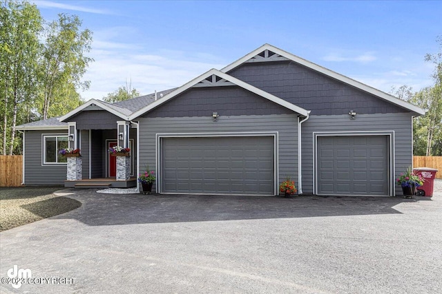 view of front facade with driveway, an attached garage, and fence