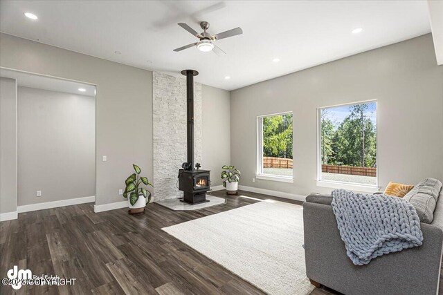 living area featuring ceiling fan, recessed lighting, wood finished floors, baseboards, and a wood stove