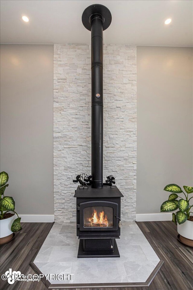 details featuring a wood stove, baseboards, wood finished floors, and recessed lighting