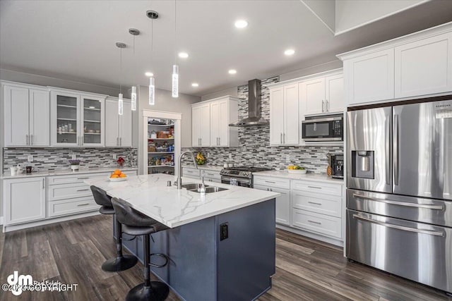 kitchen with appliances with stainless steel finishes, a sink, wall chimney range hood, and dark wood-style floors