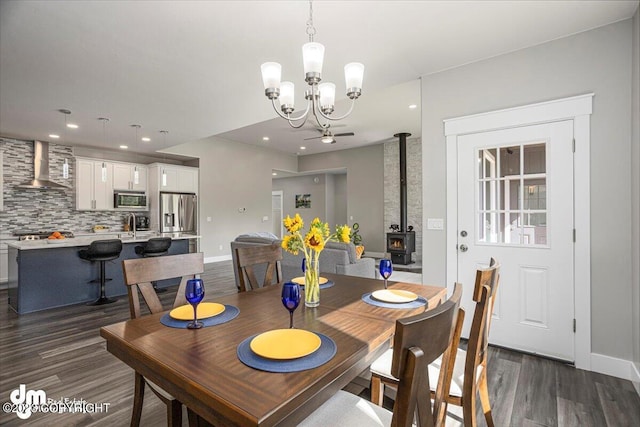 dining space with baseboards, dark wood finished floors, a wood stove, and recessed lighting