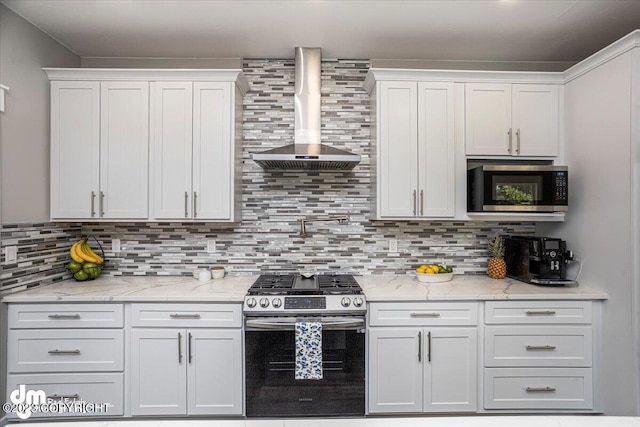 kitchen featuring stainless steel appliances, backsplash, white cabinetry, and wall chimney range hood