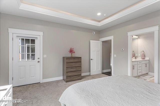 bedroom with a tray ceiling, crown molding, baseboards, and ensuite bathroom