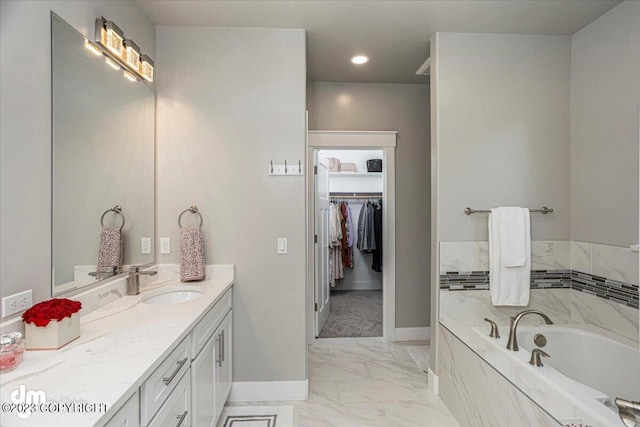 full bathroom featuring baseboards, marble finish floor, a garden tub, a spacious closet, and vanity