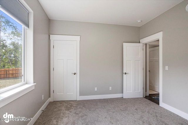 unfurnished bedroom with carpet floors, multiple windows, and baseboards