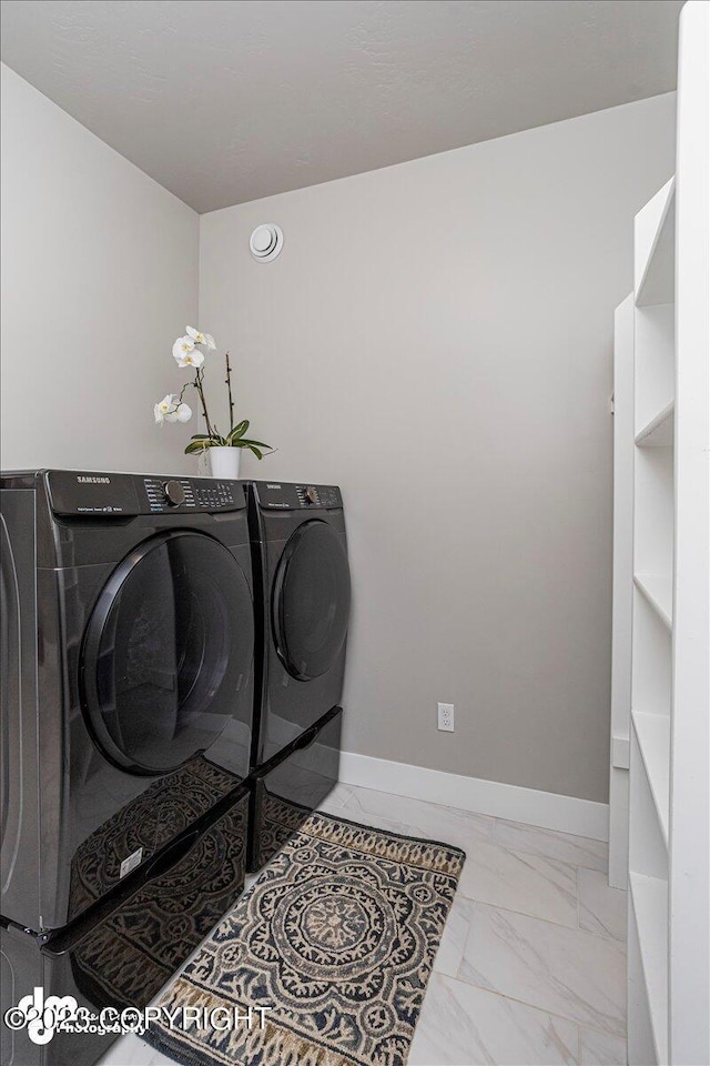 laundry room with marble finish floor, laundry area, washing machine and clothes dryer, and baseboards