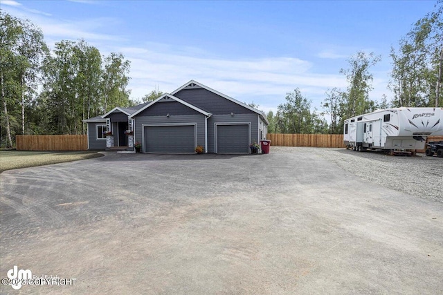 view of front facade with a garage, fence, and aphalt driveway