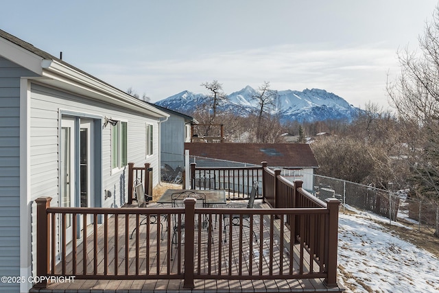 snow covered deck featuring a mountain view and fence