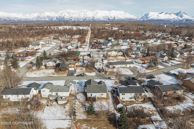 snowy aerial view featuring a mountain view and a residential view