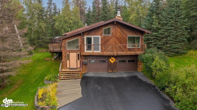 chalet / cabin with aphalt driveway, an attached garage, a chimney, and a front lawn