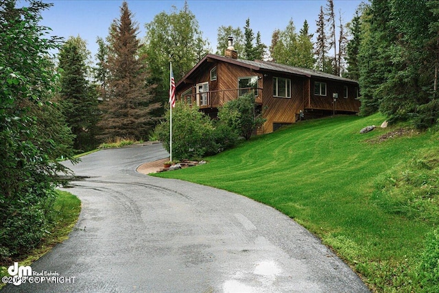 view of property exterior featuring a lawn, driveway, and a chimney