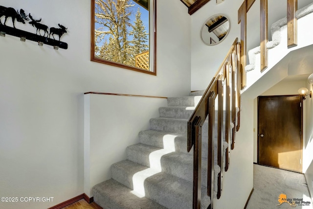 staircase featuring baseboards and a towering ceiling