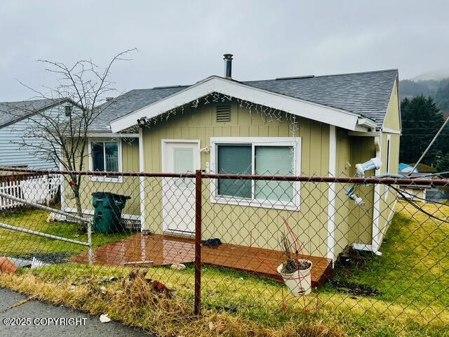 view of property exterior with a yard, roof with shingles, and fence