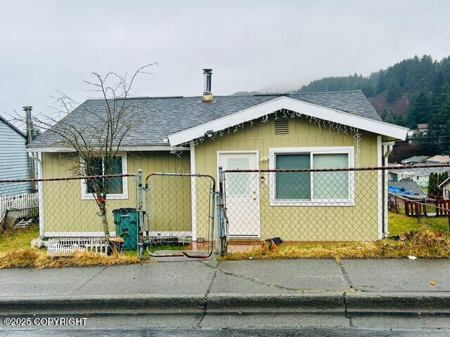 view of front of house featuring a fenced front yard, a gate, and roof with shingles