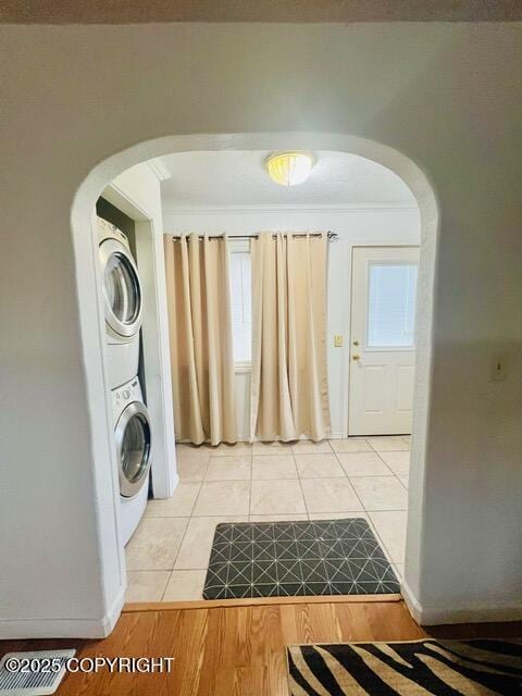 laundry area featuring stacked washer and dryer, arched walkways, laundry area, and ornamental molding