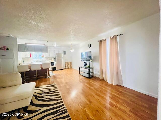 living room with light wood-style flooring, baseboards, and a textured ceiling