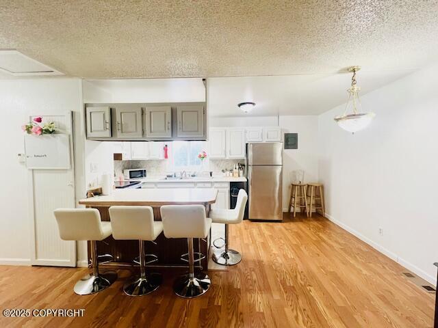 kitchen featuring stainless steel appliances, light countertops, backsplash, and light wood finished floors