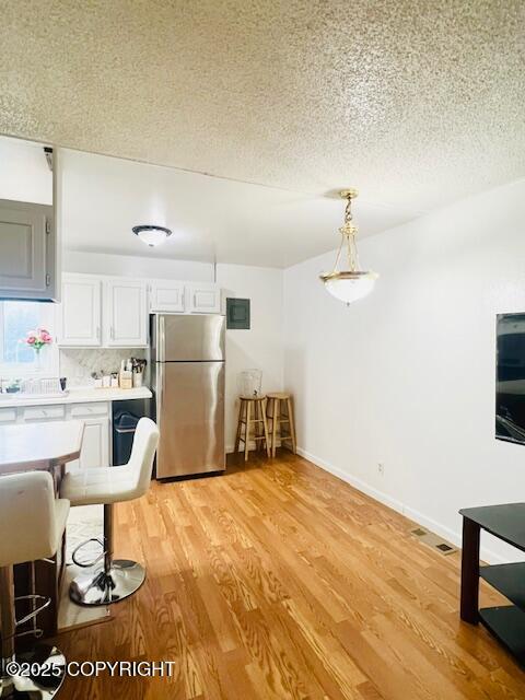 kitchen featuring light wood-type flooring, freestanding refrigerator, light countertops, and a textured ceiling