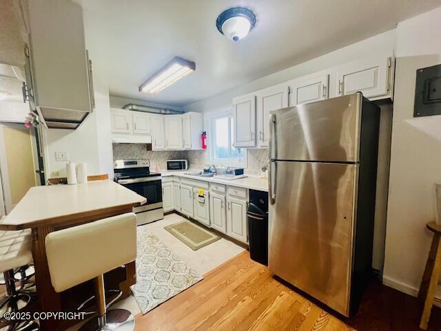 kitchen featuring light countertops, appliances with stainless steel finishes, light wood-type flooring, and backsplash