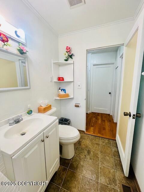 bathroom featuring ornamental molding, visible vents, vanity, and toilet