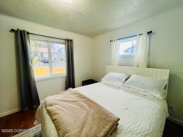 bedroom featuring dark wood finished floors, a textured ceiling, and baseboards