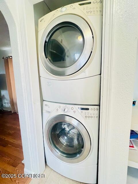 laundry room featuring stacked washer and dryer, laundry area, and wood finished floors