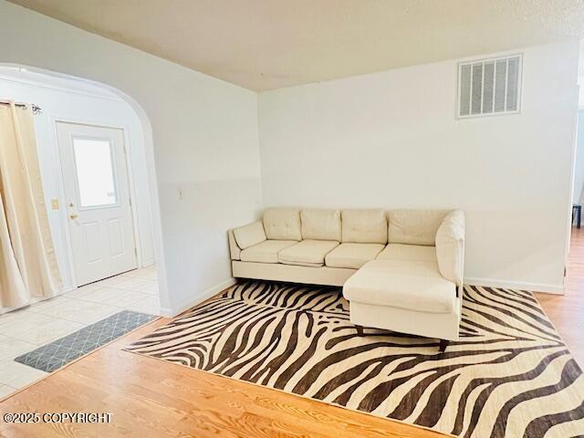 living room with wood finished floors, visible vents, and baseboards