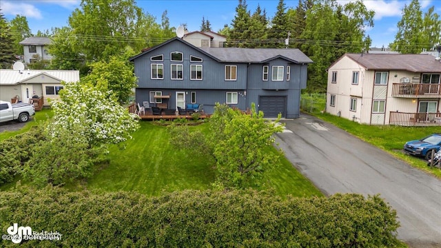 view of front of property featuring aphalt driveway, a residential view, an attached garage, and a front yard